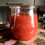 a spoon in the jar with homemade strawberry blood orange sauce.