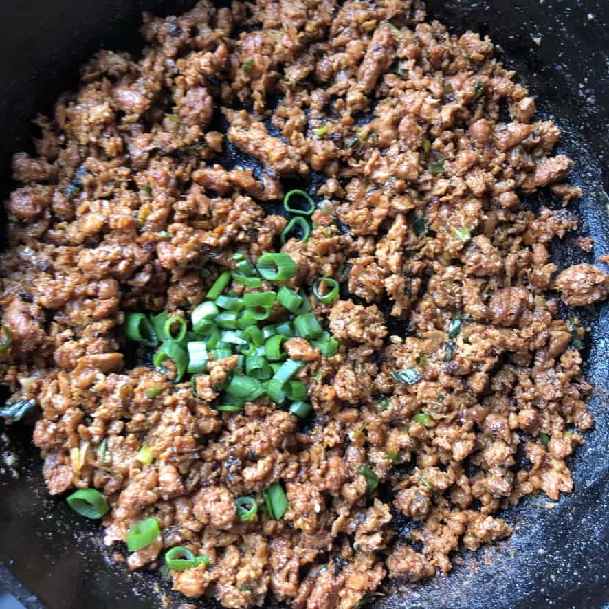 Beyond taco meat with fresh scallions being added for color and flavor.