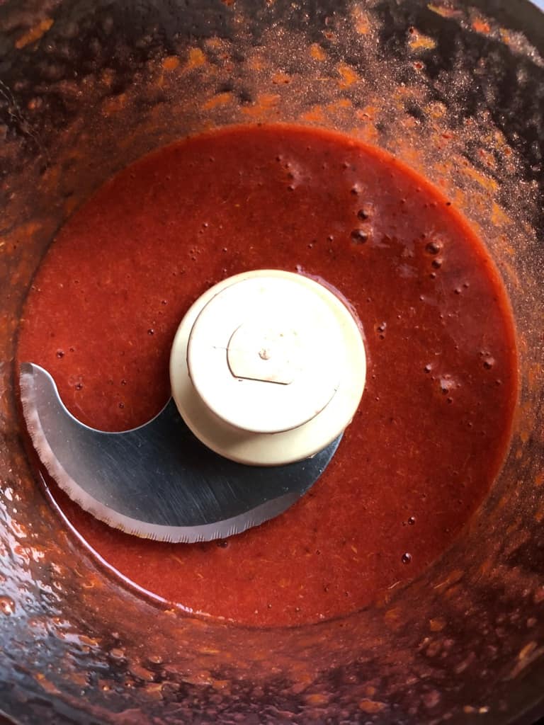 freshly pureed blood orange and strawberry sauce in the bowl of a food processor