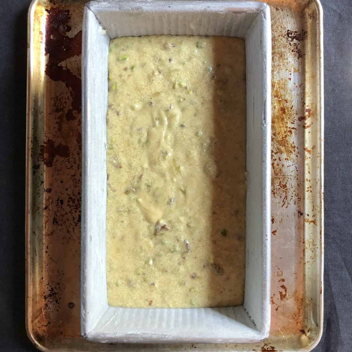 Pistachio banana bread batter in a parchment-lined loaf pan before adding the topping.
