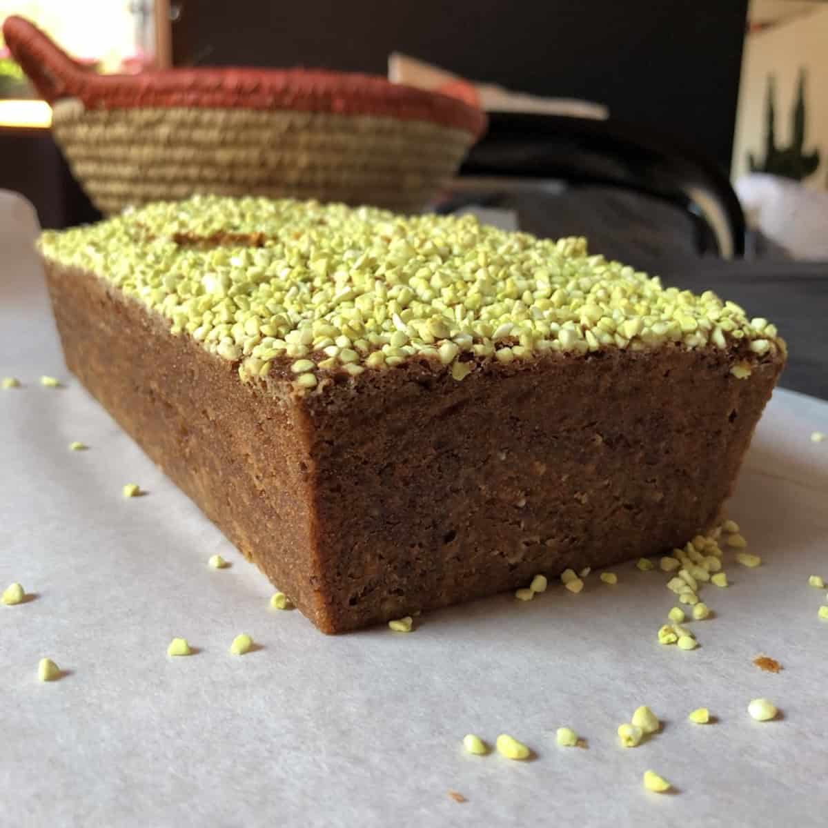 bread-whole-loaf-baked	A whole baked pistachio banana nut bread loaf topped with freeze-dried pistachios on parchment paper.
