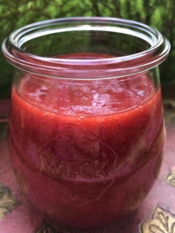 Homemade strawberry blood orange sauce in a glass Weck tulip jar, a bright red fruit sauce for topping pancakes, cheesecake, and ice cream.