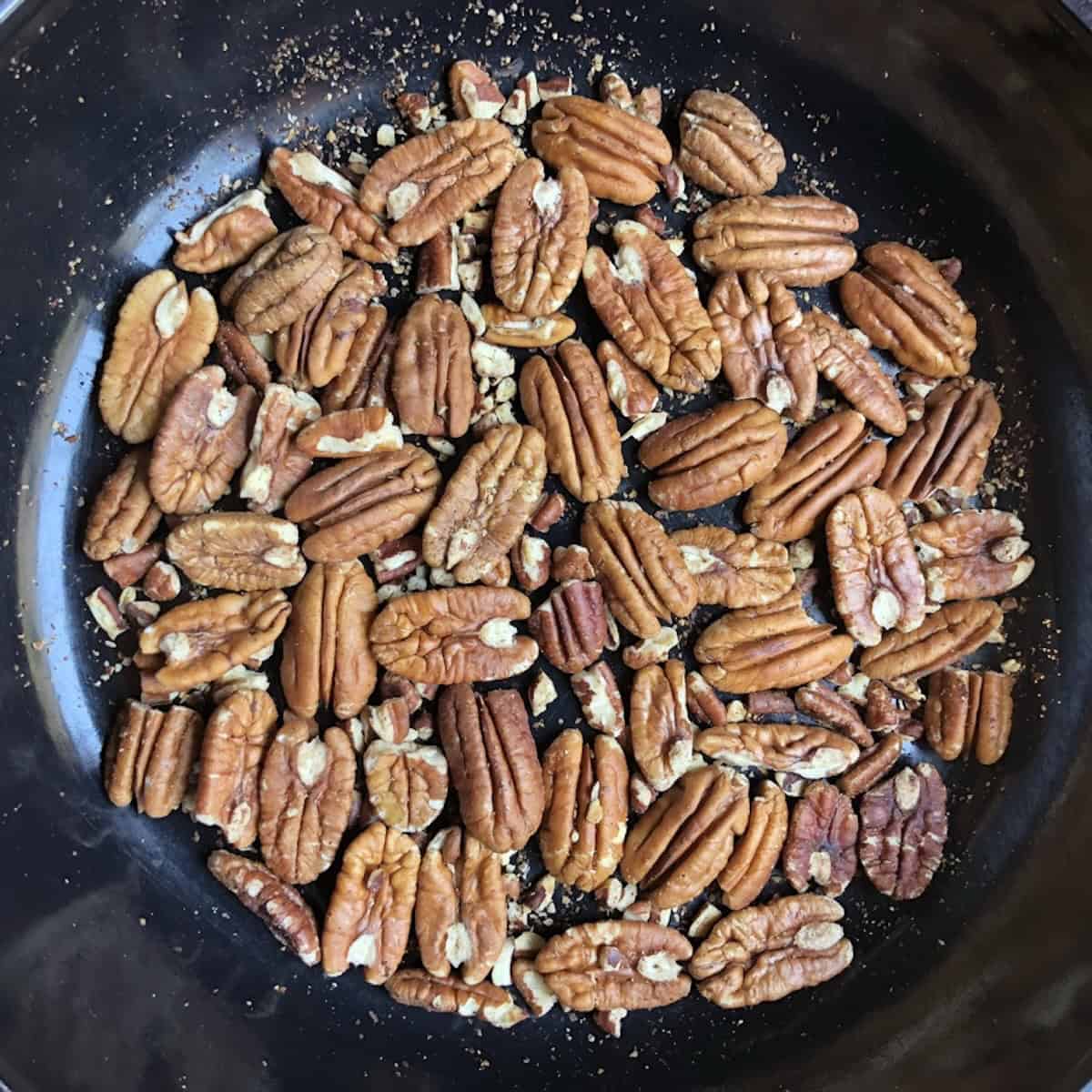 Toasting pecan halves in a skillet to add to pistachio banana bread.