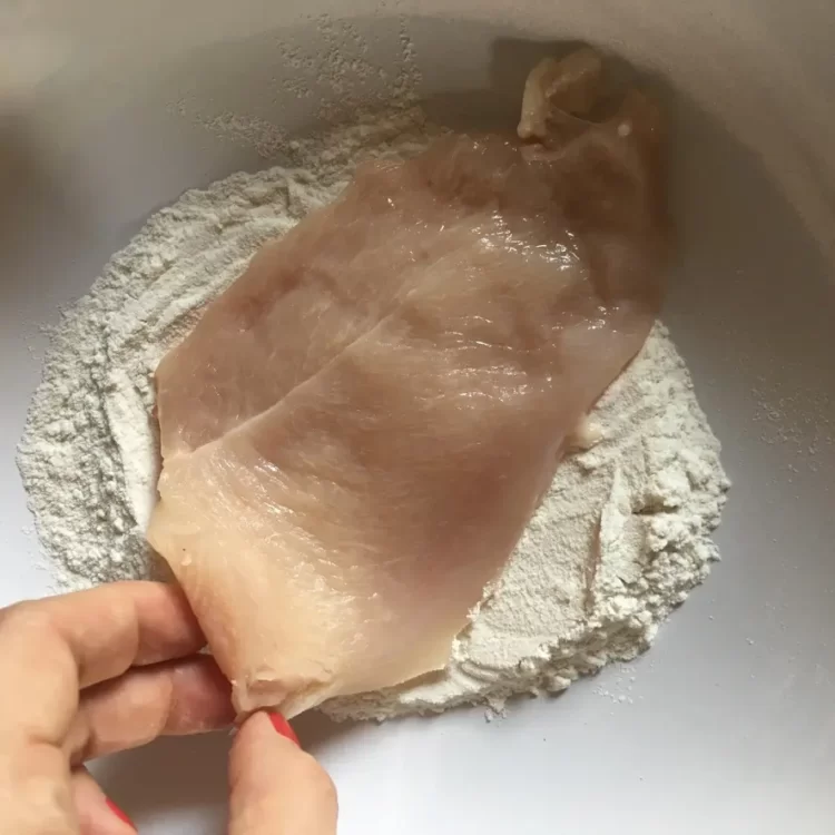 flouring chicken in a bowl