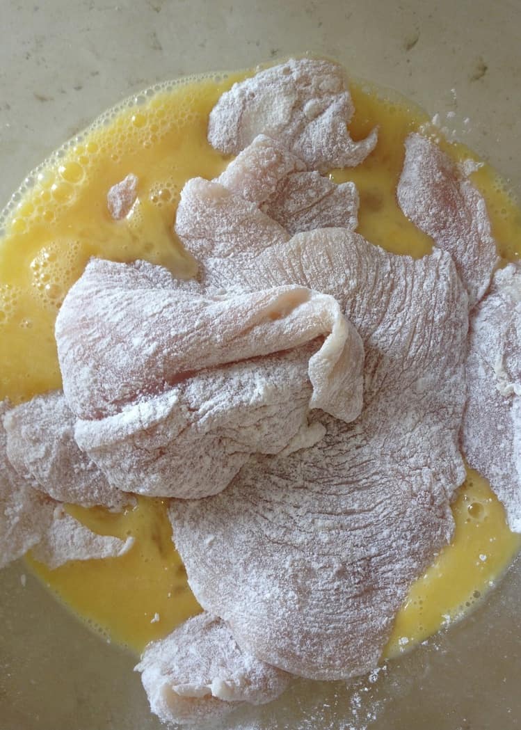 floured chicken cutlets in a bowl of beaten eggs