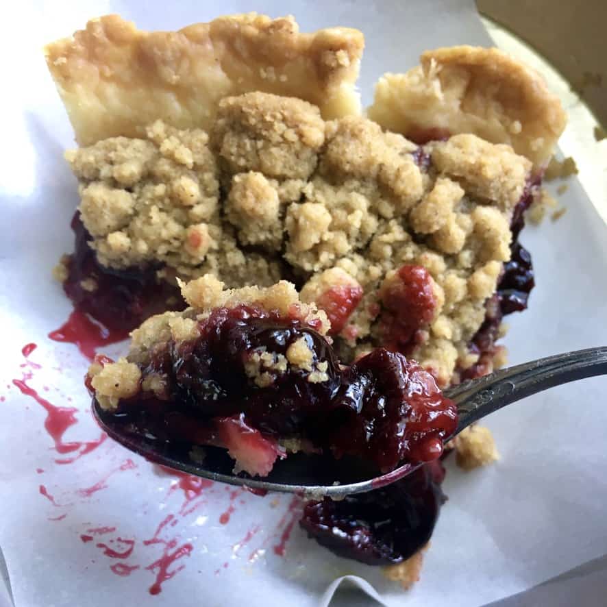 a forkful of cherry crumb crunch pie with the slice in the background