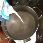 adding the coconut milk and regular milk to a sauce pot