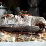 a perfect layered slice of Arkansas Possum Pie with pecan shortbread crust, sweet vanilla bean cream cheese, chocolate pudding, and sweet whipped cream and toasted pecans on top