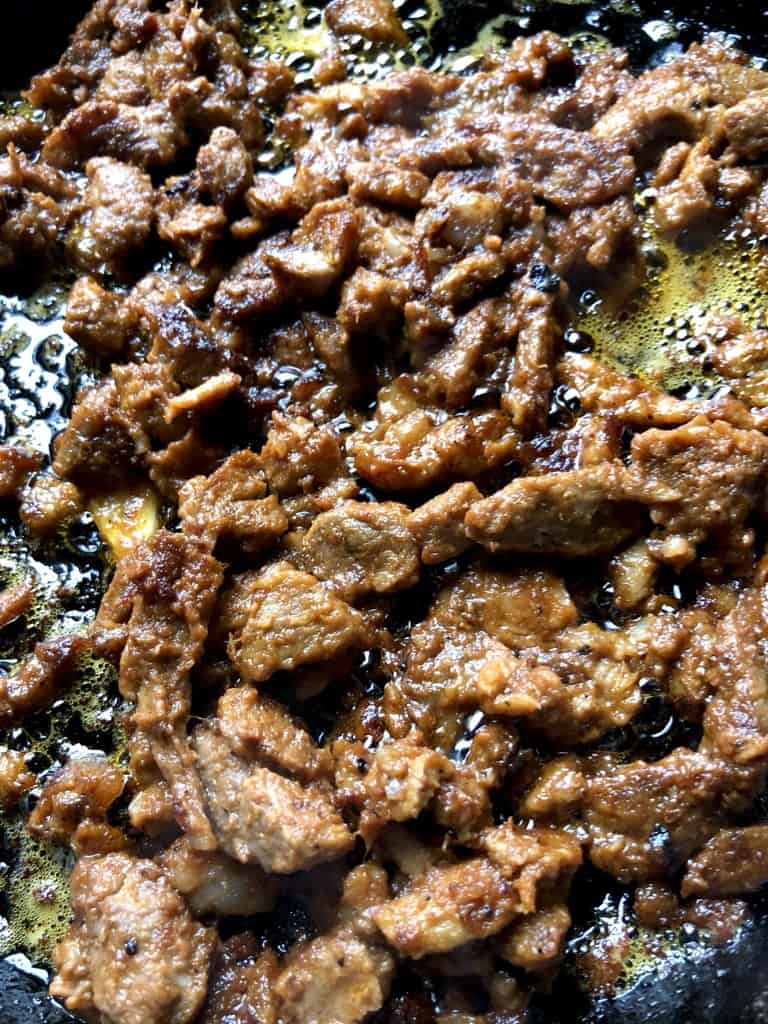 al pastor taco meat being crisped up in a hot cast iron skillet
