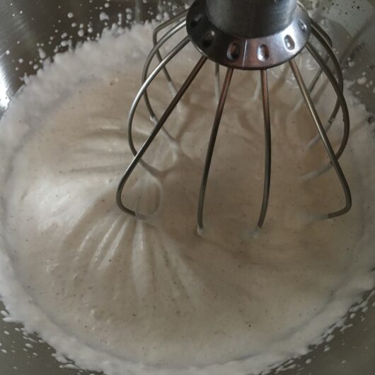 whipped cream mixture being whisked in a stand mixer