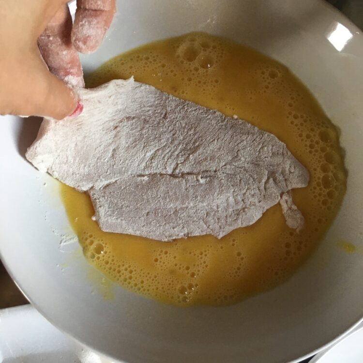 dipping floured chicken into an eggwash