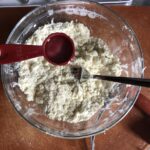 adding water one tablespoon at a time to a bowl of flour and fat
