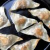 golden brown Chinese potstickers in a cast iron ckillet
