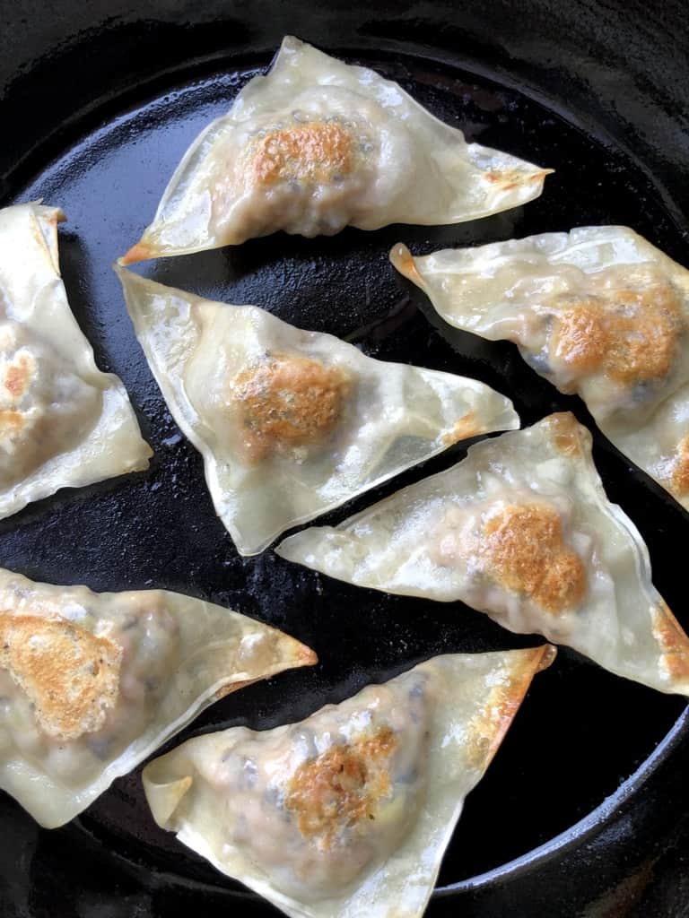 golden brown Chinese potstickers in a cast iron ckillet