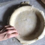 rolling the edges of the pie dough under itself