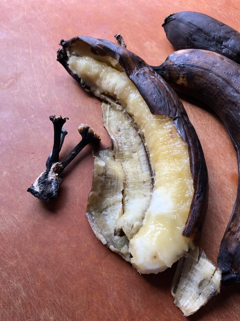 very ripe bananas still in their tobacco-colored skin with the buttery yellow flesh revealing itself