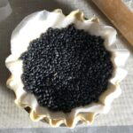 dried black beans on top of a parchment lined raw pie dough