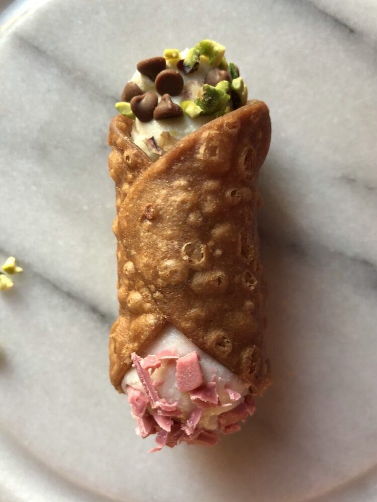 a beautiful golden brown cannoli on a marble serving platter