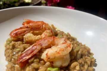 a pasta bowl plate filled lemongrass prawn risotto w/shallots and three pan-seared Argentinian red shrimp on top and speckled with green scallions