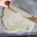 wrapping rolled out pie dough around a rolling pin to transfer it to the pie plate