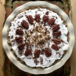 Arkansas Possum Pie decorated on top with whipped cream and toasted pecan halves and chopped pecans