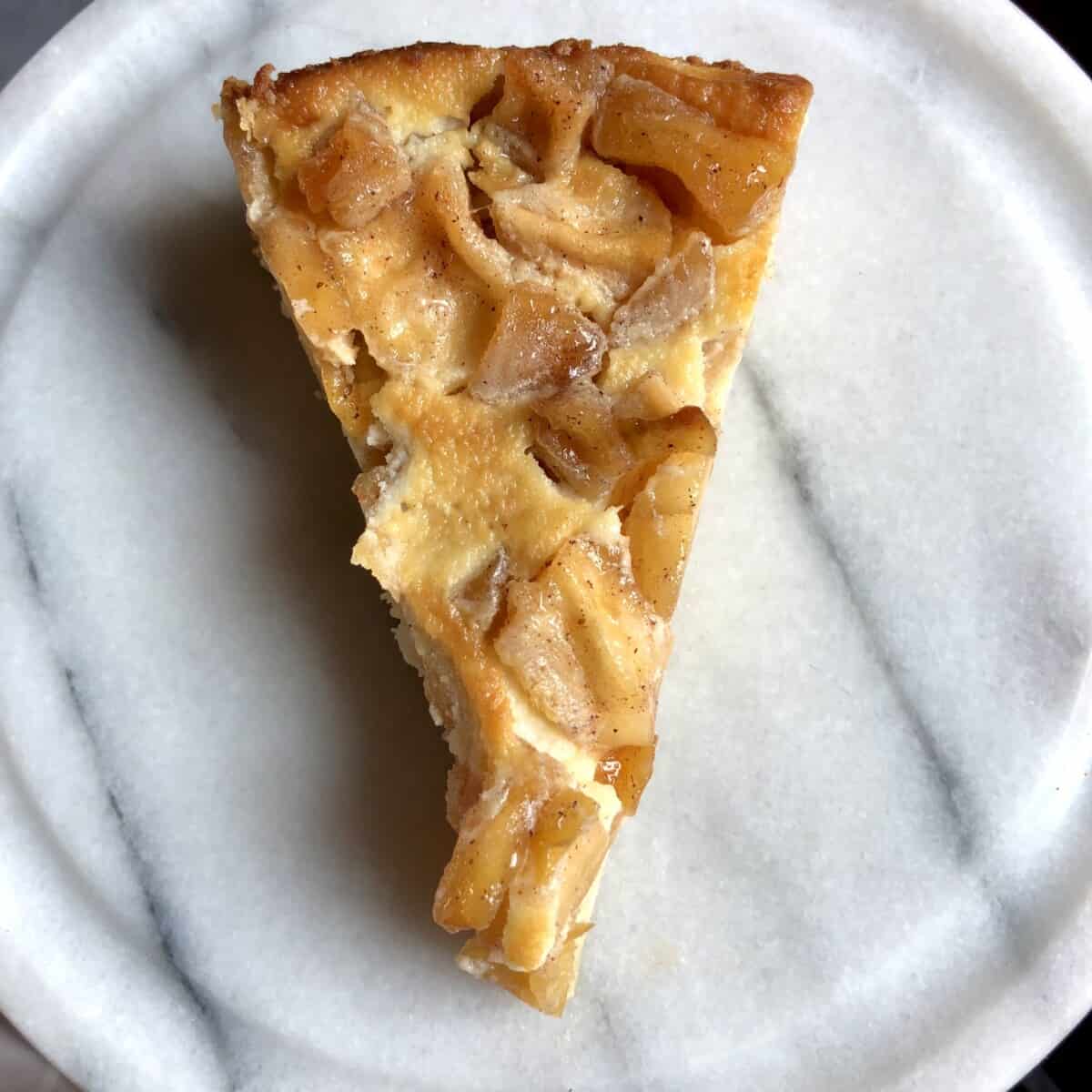 a slice of mascarpone cinnamon apple torte on a white marble serving board