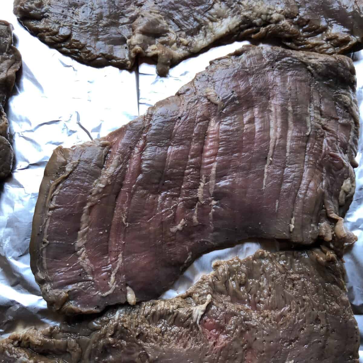 marinated and blotted dry carne asada steaks on a sheet pan lined with foil