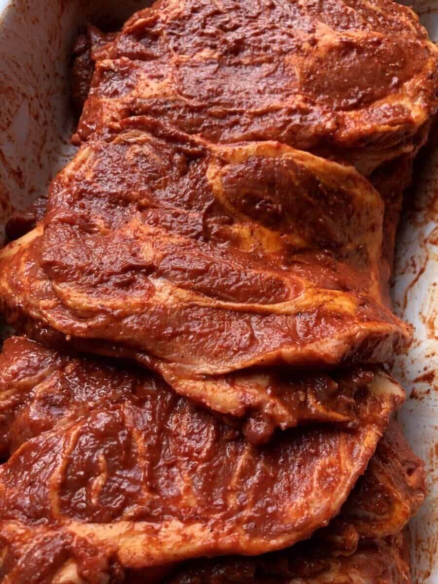 pork shoulder steaks covered in deep bright red al pastor sauce