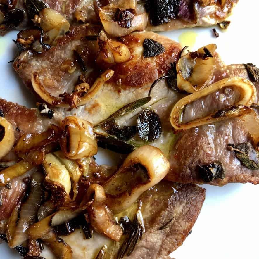 perfectly pan seared pork shoulder steaks covered in caramelized shallots, sage, rosemary and drizzled with extra virgin olive oil