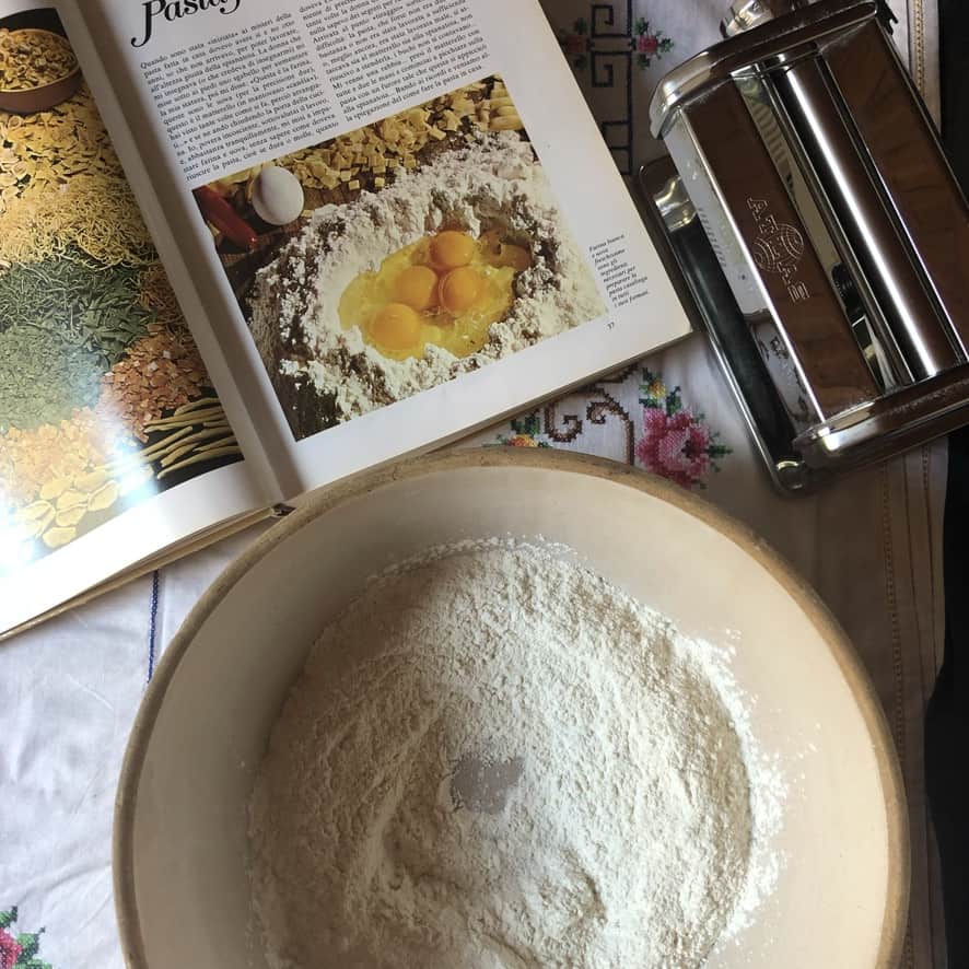 a vintage bread bowl with 00 flour in it and a well made in the middle
