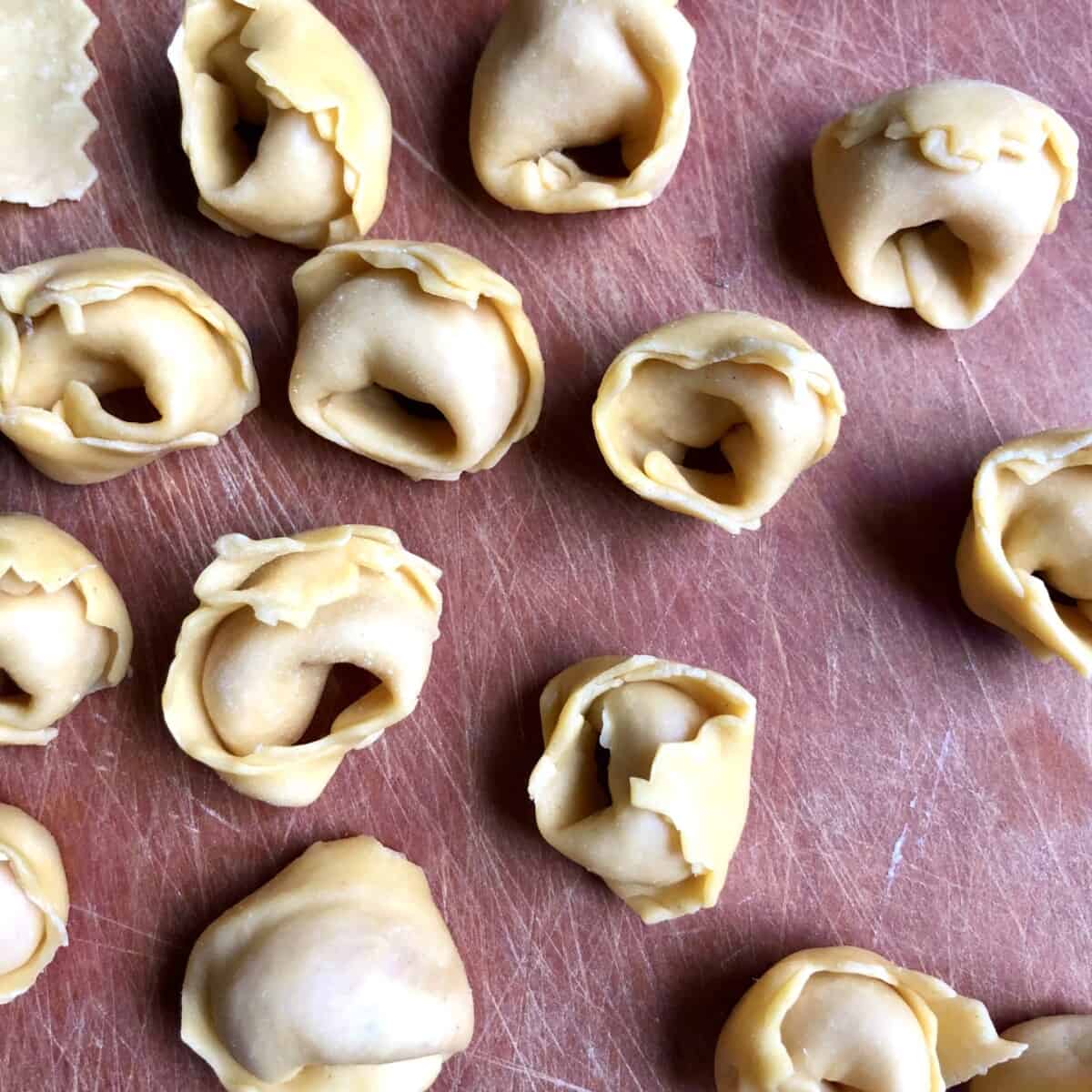 homemade tortellini on a cutting board after just being filled