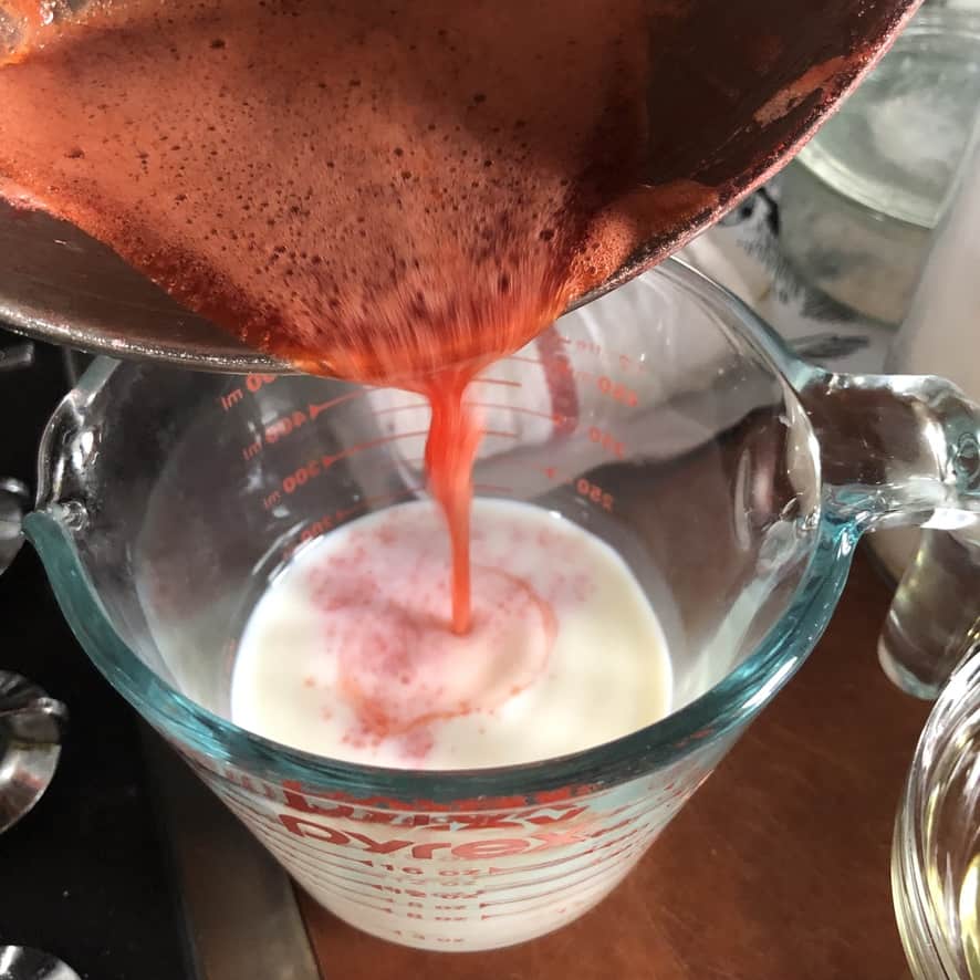 pouring the reduced strawberry juice into the milk mixture