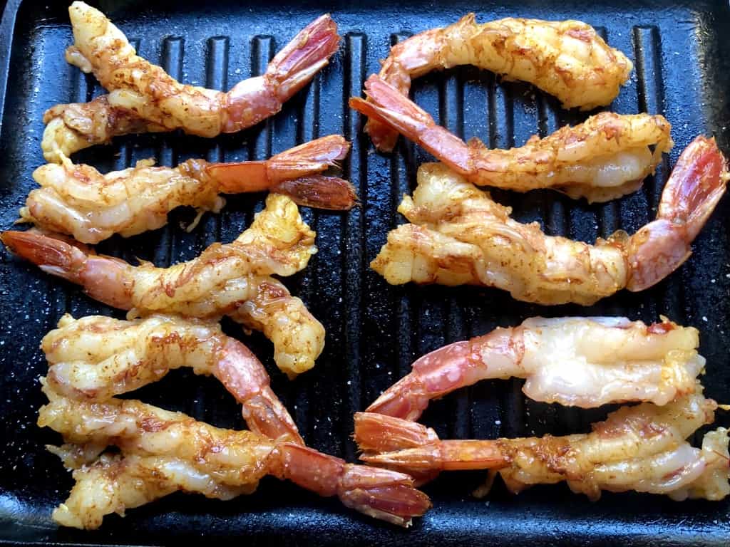 10 butterflied Argentinian Red shrimp seasoned and cooking on a grill pan