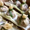 just steamed homemade money bag dumplings or beggar's purses in a bamboo steamer sitting on top of nappa cabbage leaves