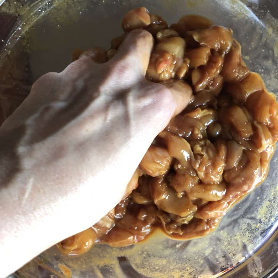 my hand massaging in the velveting mixture into the sliced chicken so it will soak it up