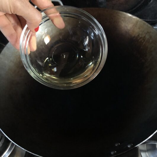 adding 1 tablespoon of oil to the wok as it heats up