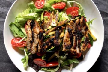 a mixed baby green salad with pan-seared julienned zucchini, fresh garden datterini tomatoes, and sliced smoky grilled pork steaks