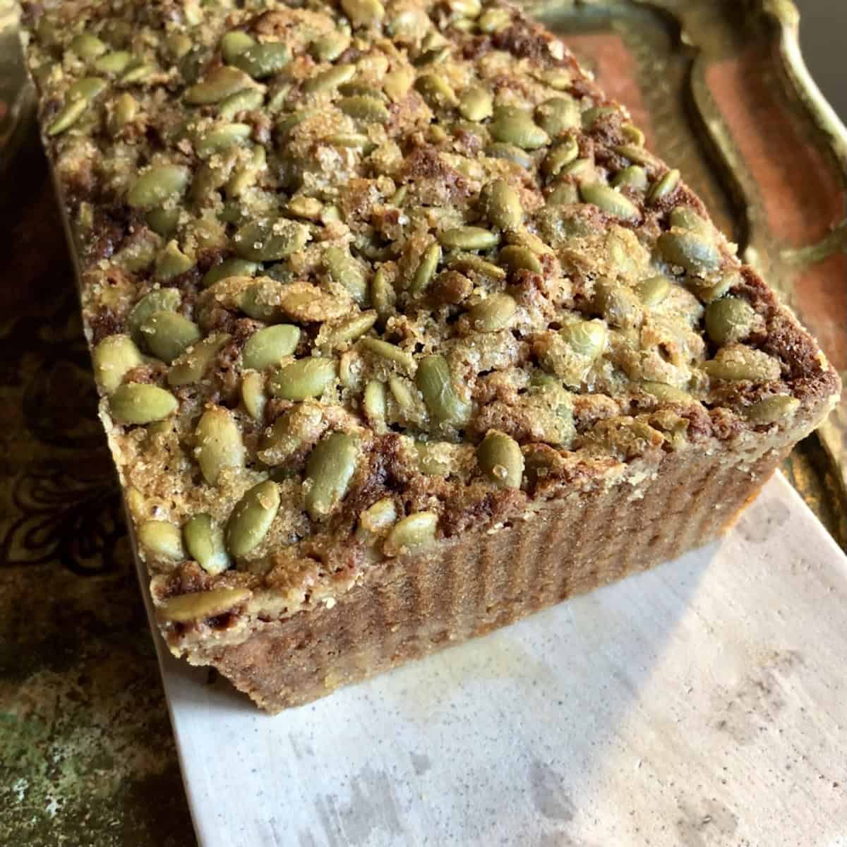 Closeup of a loaf of pumpkin seed banana bread with a crunchy pumpkin seed topping baked golden brown.