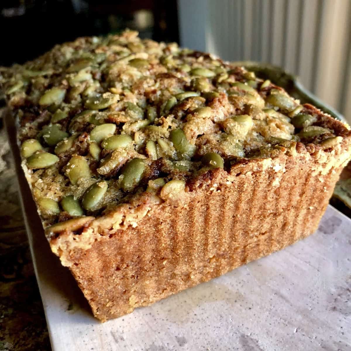 Another closeup of a loaf of pumpkin seed banana bread with a crunchy pumpkin seed topping baked golden brown.