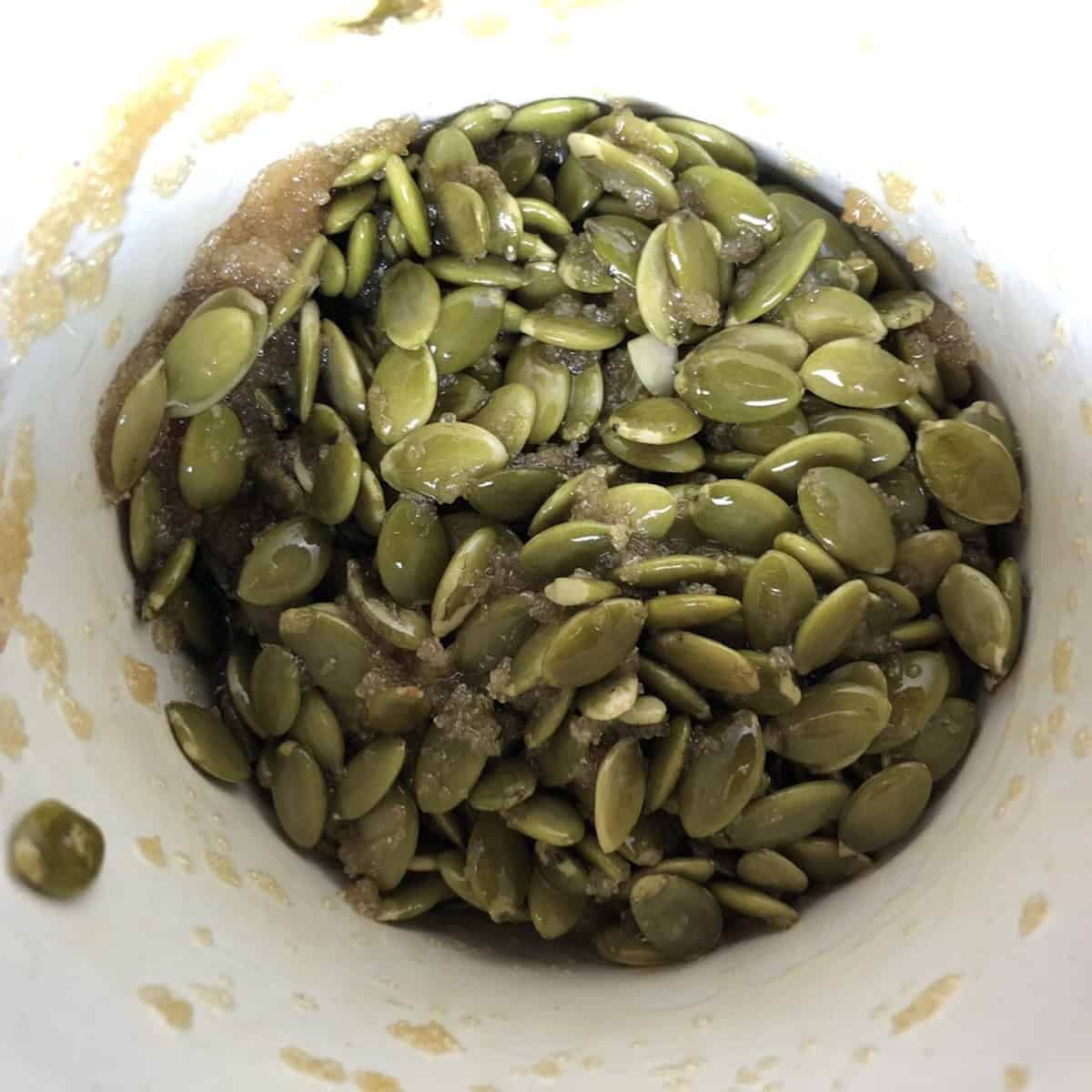 Homemade pumpkin seed crunch made with melted butter, raw coarse sugar, a pinch of salt, and raw pumpkin seeds for topping banana bread with pumpkin seeds.