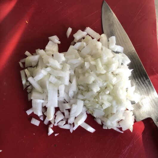 chopped onions on a red cutting board