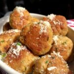 golden brown chicken and pork meatballs in a ceramic dish sprinkled with grated parm and chives