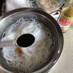 adding light soy sauce and a little oil to the glass noodles to season them before cutting and adding to the spring rolls