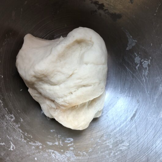 homemade dumpling dough in a mixing bowl after just coming together and still jagged