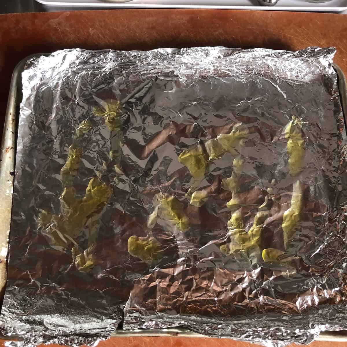 Aluminum foil lined baking sheet brushed with extra virgin olive oil to prepare for baking homemade chicken and pork meatballs.