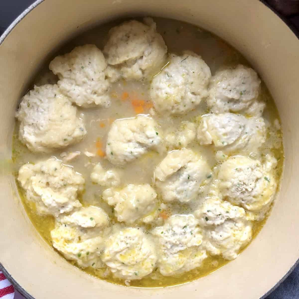 Raw drop dumplings covering the top of the simmering chicken soup base before adding the lid to steam for 15 minutes.