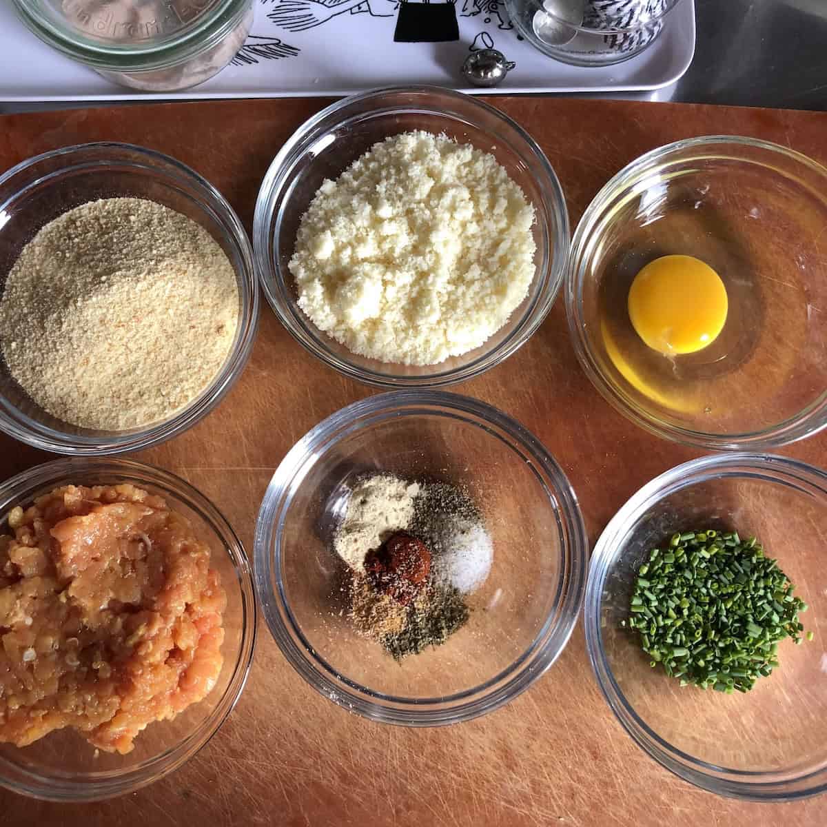 Chicken and pork meatball recipe ingredients assembled on a cutting board ready to be mixed together for homemade Italian meatballs.