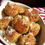 Golden brown chicken and pork meatballs in a ceramic dish sprinkled with grated parmesan cheese and chives.