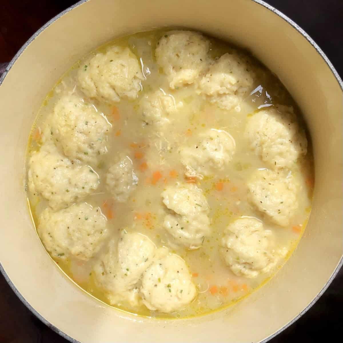 Perfectly cooked fluffy drop dumplings in a pot of creamy chicken and dumplings ready to garnish with parsley and serve.
