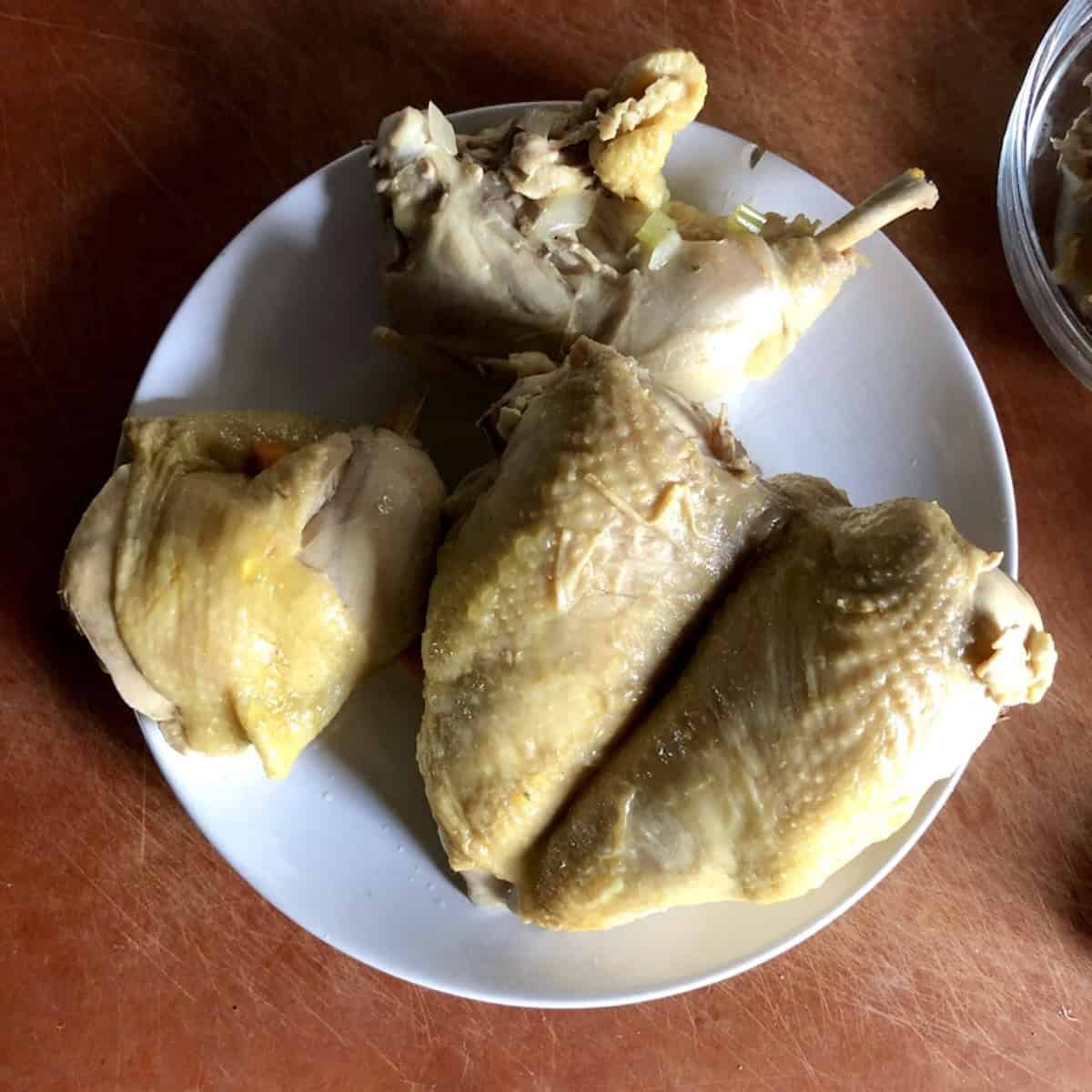 Cooked whole chicken removed from the soup base to cool before deboning for creamy chicken and dumplings.